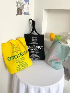 Detail of canvas tote bags in yellow, black and green with grocery text print
