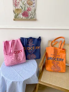 Detailed view of large canvas tote bags with Grocery print in pink, navy and orange