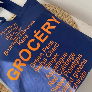 Detail of blue canvas tote bag showing clear orange grocery print and fabric texture