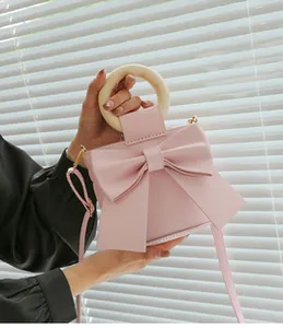 Detail of pink bow-knot mini bag with wooden ring handle and crossbody strap