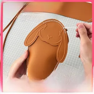 DIY brown rabbit coin purse kit showing hand sewing process on a grid cutting mat