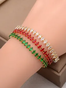 Dettaglio di bracciali dorati con zirconi taglio marquise in verde, rosso e bianco