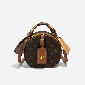 Detail der runden Retro-Umhängetasche mit Monogramm-Print und Seidentuch-Dekoration