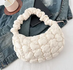 Close-up of cream quilted cloud bag with ruched handle and pink ribbon detail