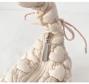 Detail view of smooth silver metal zipper and pink drawstring on white cloud bag
