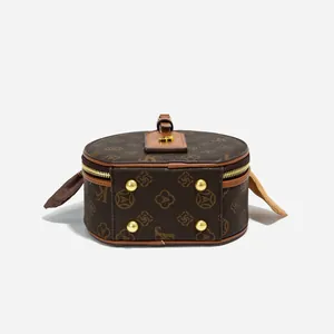 Makroaufnahme von braunem Vintage-Monogramm-Muster und Goldreißverschluss an runder Tasche