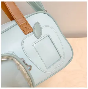 Détail de la fente PVC en forme de pomme sur le sac bleu clair en similicuir