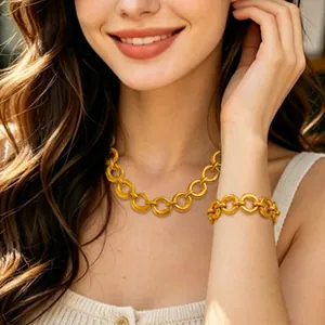 Detail view of a gold-toned circular link necklace and bracelet set on a female model