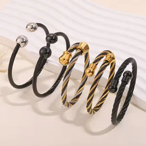 Five titanium steel twisted rope bangles in black and gold shown on a white display