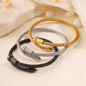 Detailed view of three twisted cable bracelets in gold, silver, and black finishes.