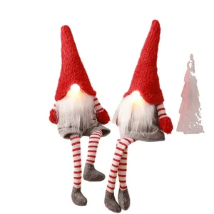 Paire de gnomes de Noël en peluche avec nez lumineux et jambes rayées sur fond blanc