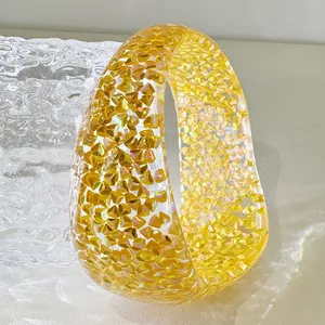 Detailed view of a thick clear resin bangle bracelet with vibrant gold glitter flakes