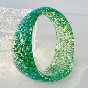 Macro detail of a green resin bangle featuring sparkling holographic glitter foil inclusions