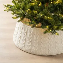 Close-up view of a premium white cable-knit Christmas tree collar on wood floor