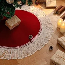 Detailed view of red Christmas tree skirt with white tassel fringe in festive setting.