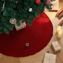 Elegant red knitted Christmas tree skirt with ruffled edges in a cozy festive scene
