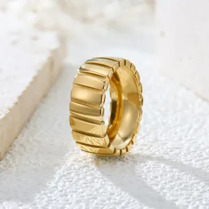 Close-up macro detail of a vintage gold ribbed stainless steel ring on a white stone background