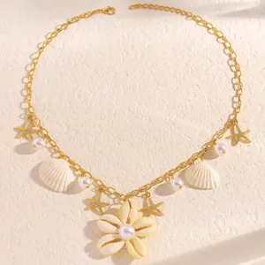 Dettaglio della collana dorata stile spiaggia con conchiglie, stelle marine e perle.