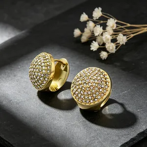 Détail de boucles d'oreilles créoles en acier doré serties de strass pavés