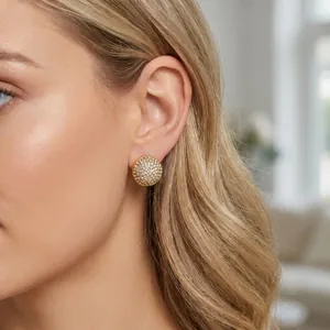 Détail de boucles d'oreilles dôme dorées élégantes avec cristaux sur le mannequin
