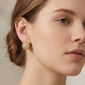 Gros plan d'une femme portant des boucles d'oreilles ovales pavées dorées