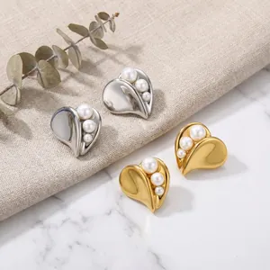 Detailed view of elegant gold and silver heart-shaped pearl earrings on white marble