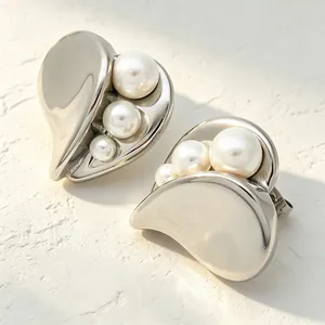 Detailed macro view of asymmetrical stainless steel heart earrings with inlaid pearl accents