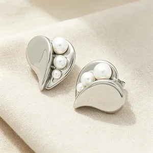 Close-up of heart-shaped stainless steel earrings with elegant inlaid white pearls