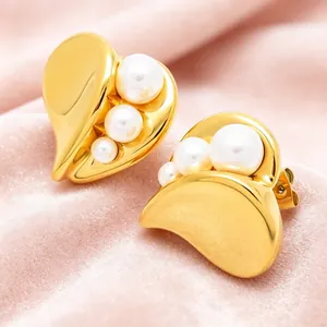 Macro detail of French style asymmetric gold-tone heart earrings with white pearls