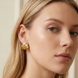 A macro detail view of elegant gold heart-shaped earrings with pearls on a model