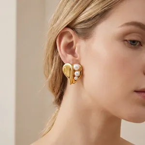 Close-up of elegant gold heart-shaped stainless steel earring with pearl accents on model