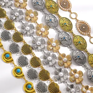 Détail de chaînes de taille ethniques or et argent avec breloques coquillage et fleur