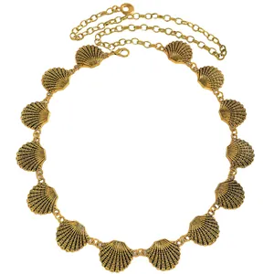 Détail d'une chaîne de taille dorée avec breloques en forme de coquillages pour robe.