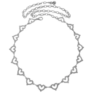 Détail d'une ceinture chaîne argentée en forme de cœur avec strass brillants.