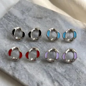 Detail of irregular stainless steel geometric earrings with multi-color enamel inlay.