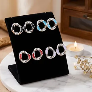 Macro view of four pairs of multi-color oil-dripped stainless steel earrings on a display