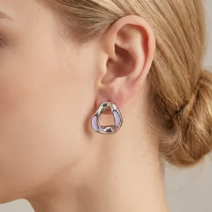 Macro detail of an elegant silver wavy earring with lavender enamel on a model's ear