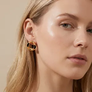 Close-up of elegant gold irregular circular earring with black enamel on female model