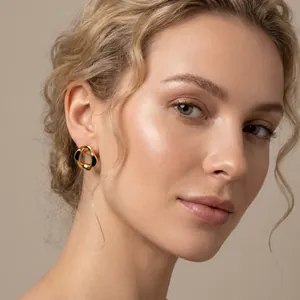 Close-up of elegant gold-toned wavy geometric earrings with black enamel detail
