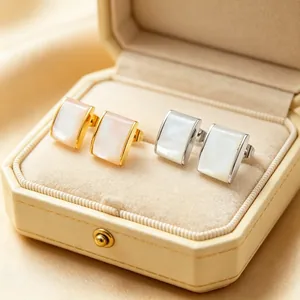 Detail of gold and silver stainless steel rectangular earrings with shell inlay