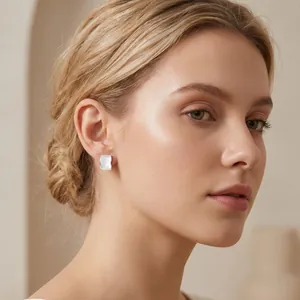 Detailed view of a woman wearing minimalist stainless steel square shell stud earrings.