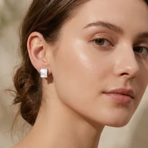 Detailed close-up of square stainless steel shell stud earrings worn by a model.