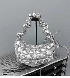 Close-up of silver crescent handbag with heart quilted patterns on a metal shelf