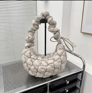 Detailed view of heart-shaped quilting and ruched handle on apricot underarm bag
