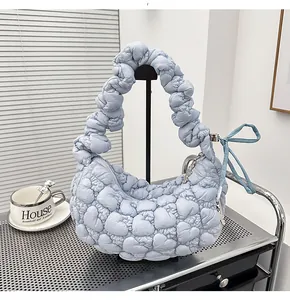 Detail of light blue quilted heart texture and ruched handle on the crescent bag