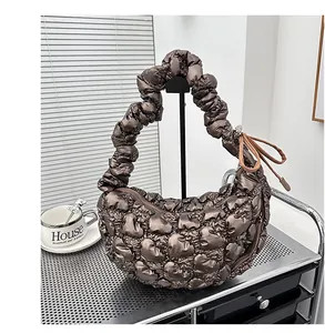 Detail of a brown quilted cloud bag featuring metallic texture and gathered handle
