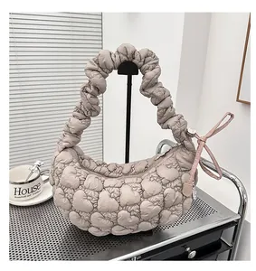 Detail of beige heart-shaped quilted puff texture bag with pink bow on metal cart