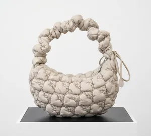 Close-up of heart-shaped quilting and ruffled handle on beige nylon cloud bag