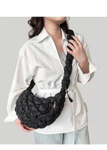 Detail view of black pleated cloud bag with chunky woven strap and glossy texture