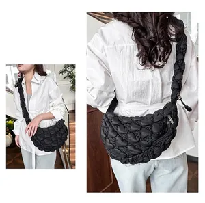 Detail of black quilted heart pattern crossbody bag with a wide pleated shoulder strap